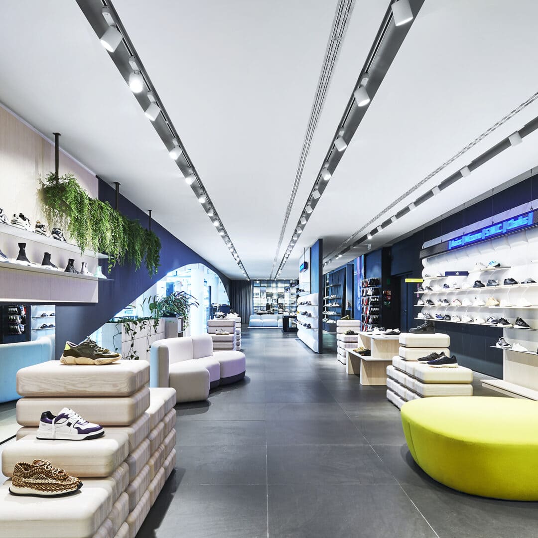 Modernes Schuhgeschäft mit vielfältiger Auswahl an Schuhen, bequemen Sitzgelegenheiten und ansprechender Ladenarchitektur. Perfekt für Kunden, die hochwertige Schuhe suchen.