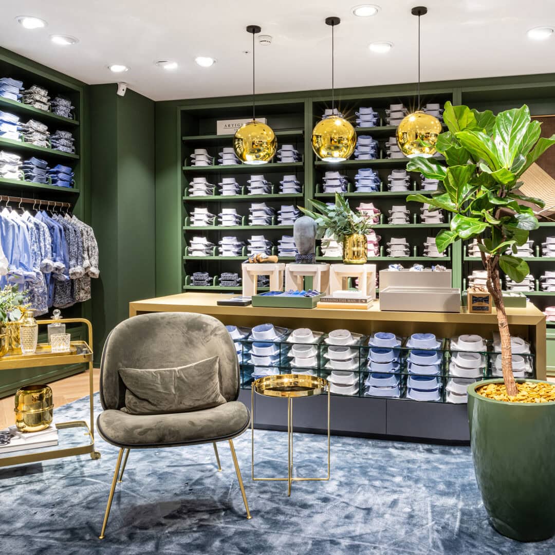 Modernes KRAISS Geschäft mit gut sortierten Regalen voller Textilien, stilvoller Einrichtung und grüner Pflanze, die eine einladende Atmosphäre schafft.