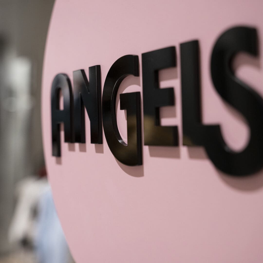 Nahaufnahme eines pinkfarbenen Schilds mit schwarzen 3D-Schriftzug 