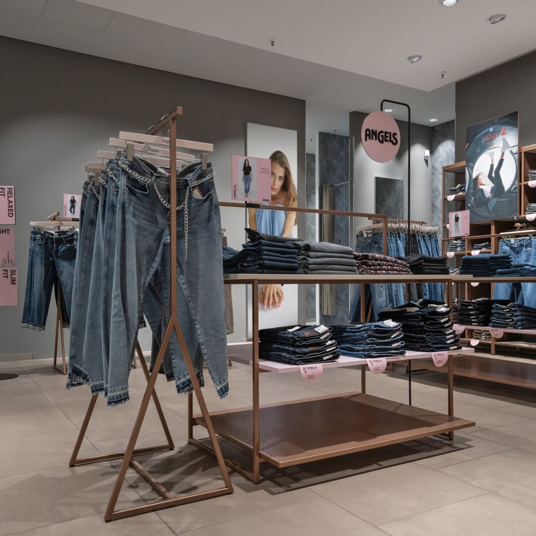 Modischer Damenjeans und Kleidung im Angels Store, präsentiert auf stilvollen Kleiderständern in einem modernen Modegeschäft.