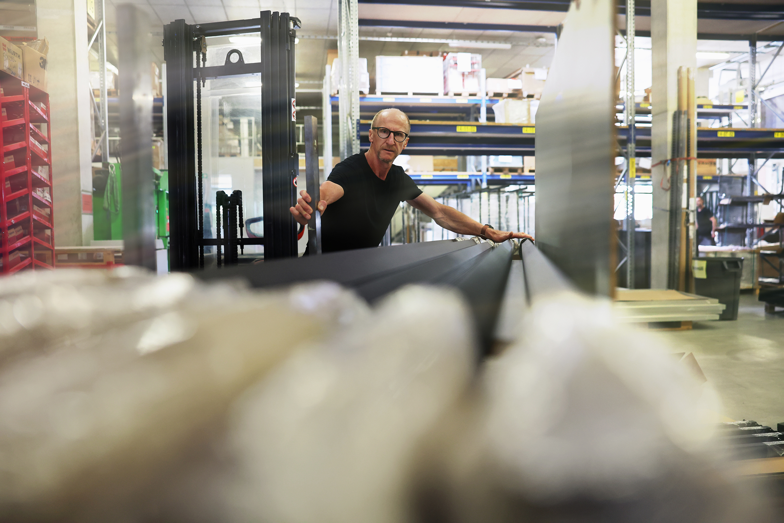 Mitarbeiter in einer Fertigungshalle bei KRAISS, umgeben von Regalen und Produktionsmaterialien, mit gut ausgeleuchteten Arbeitsbereichen.