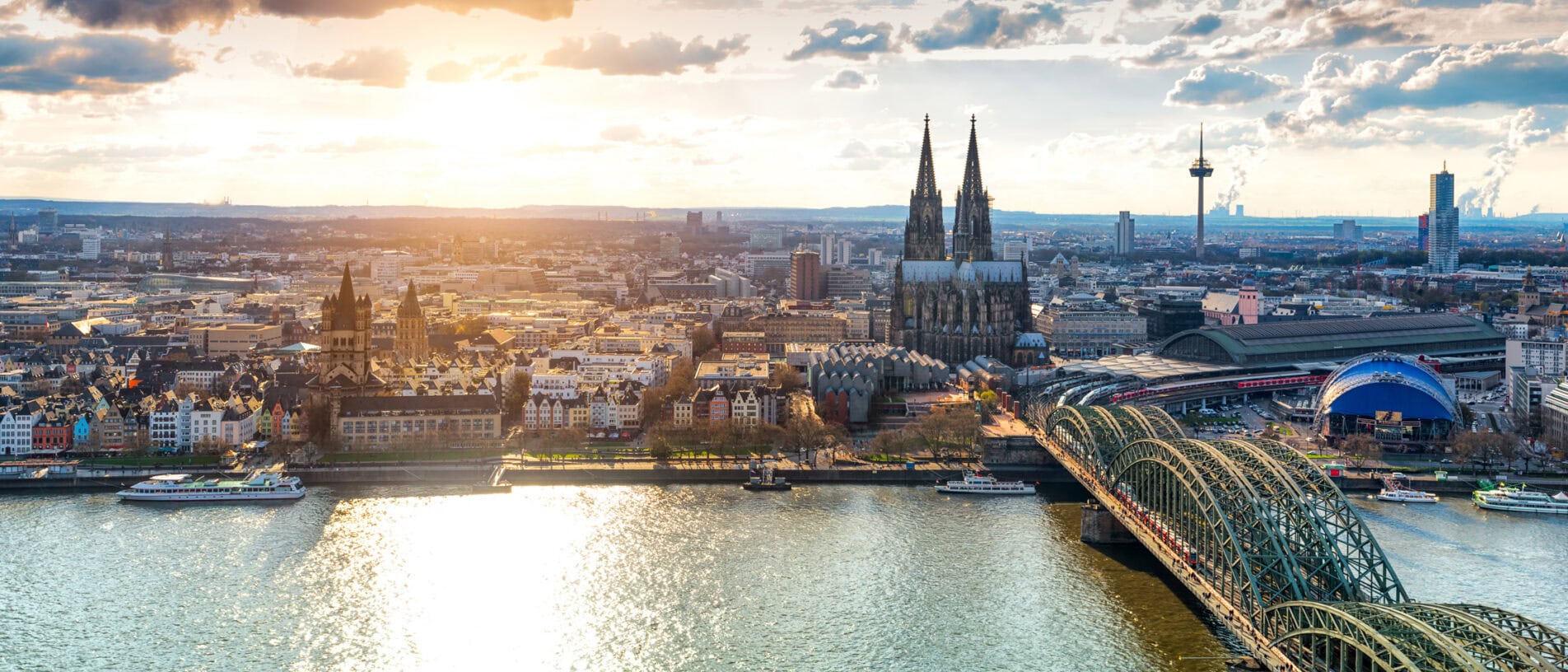 Blick auf die Kölner Skyline mit Dom und Rhein bei Sonnenuntergang, repräsentativ für Ladenbau-Designs in Köln.