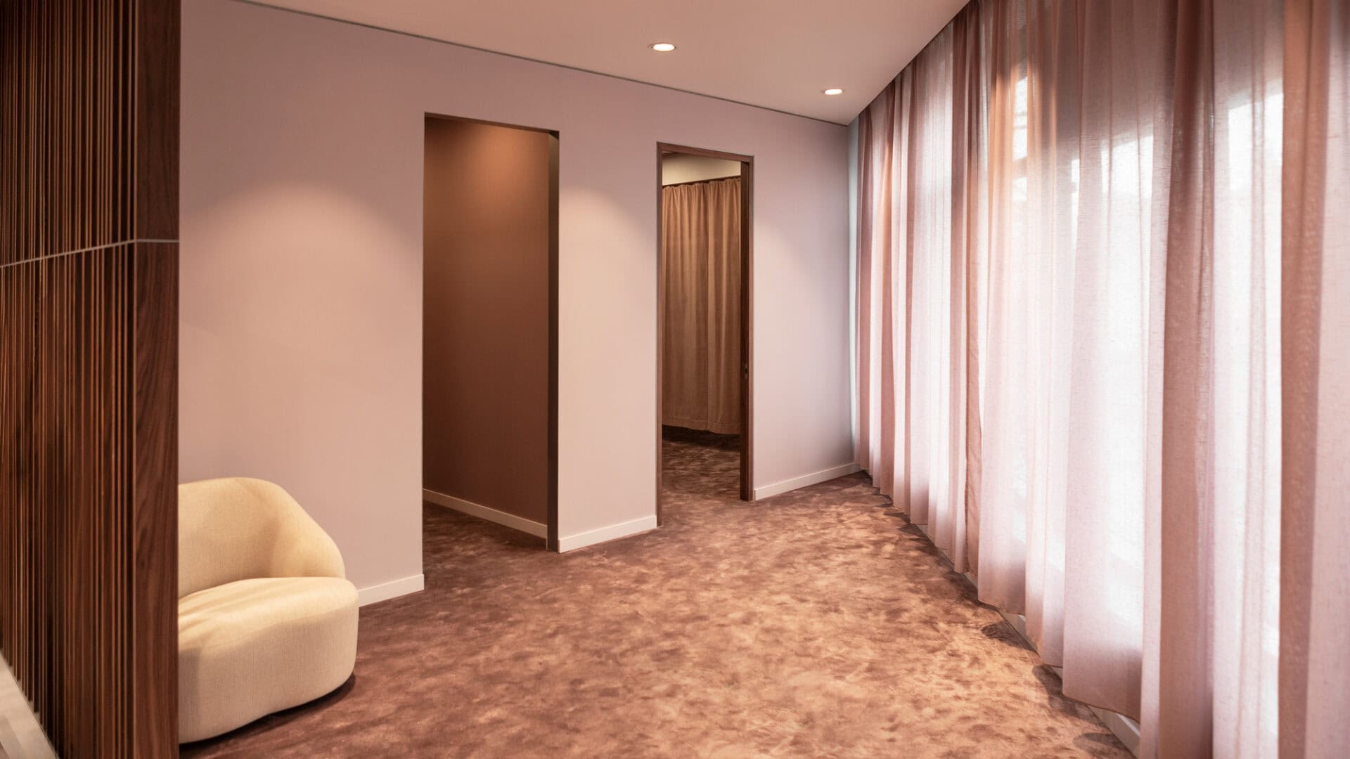 Helles Hotelzimmer mit großen Fenstern, Vorhängen und gemütlicher Einrichtung, ideal für einen komfortablen Aufenthalt.