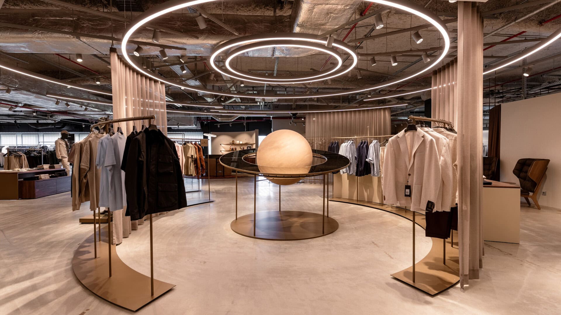 Moderne Modeboutique mit runden Lichtinstallationen und eleganten Kleiderständern, stilvolle Einkaufserfahrung bei KRAISS.