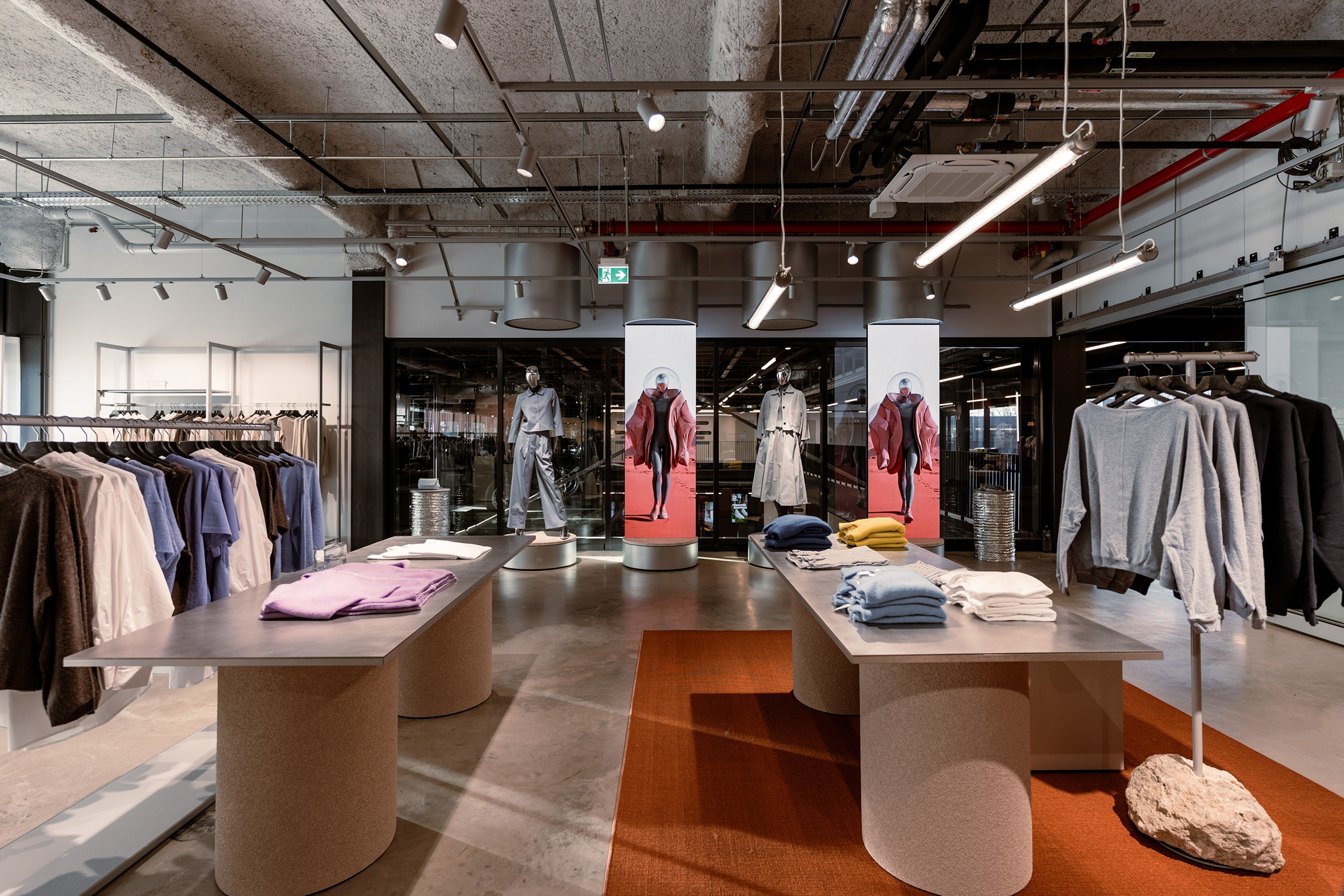 Moderne Modeboutique mit Kleidung auf Tischen und Kleiderständern, stilvolles Einkaufserlebnis bei KRAISS in Deutschland.