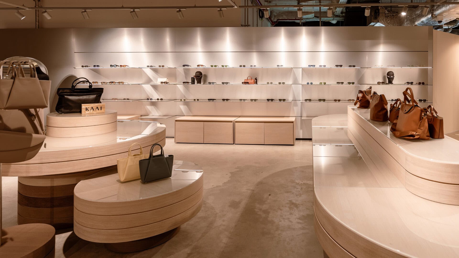 Innenansicht des KRAISS Stores mit Taschen und Accessoires auf weißen Regalen und Displays, moderne und elegante Präsentation.