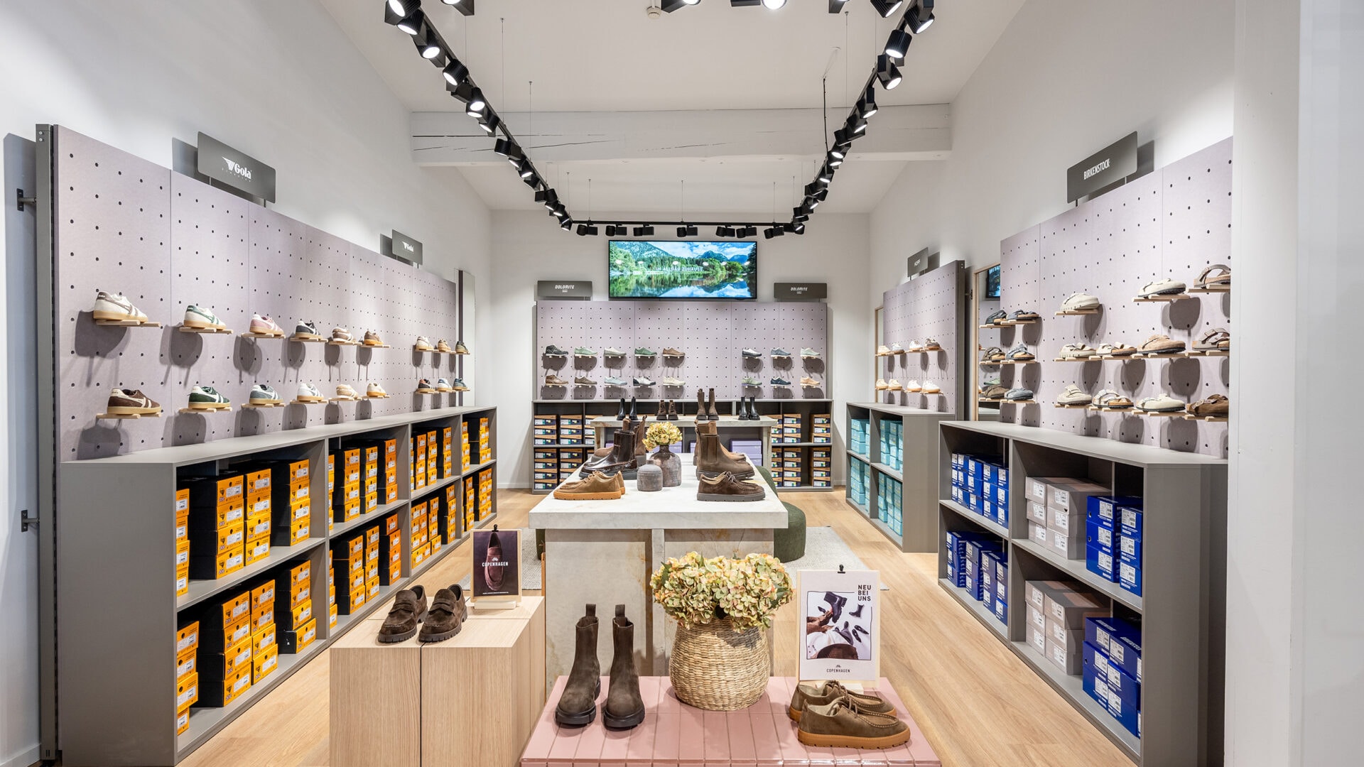 Innenansicht eines Ladenlokals mit Schuhregalen, Schuhen und einer Deckenbeleuchtung.