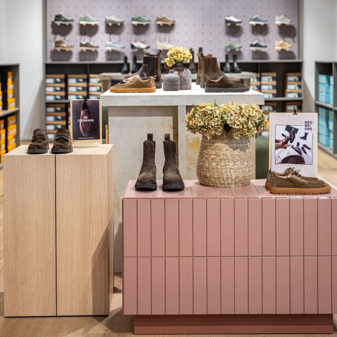 Innenansicht eines Schuhgeschäfts mit Schuhen auf Displays und Regalen.