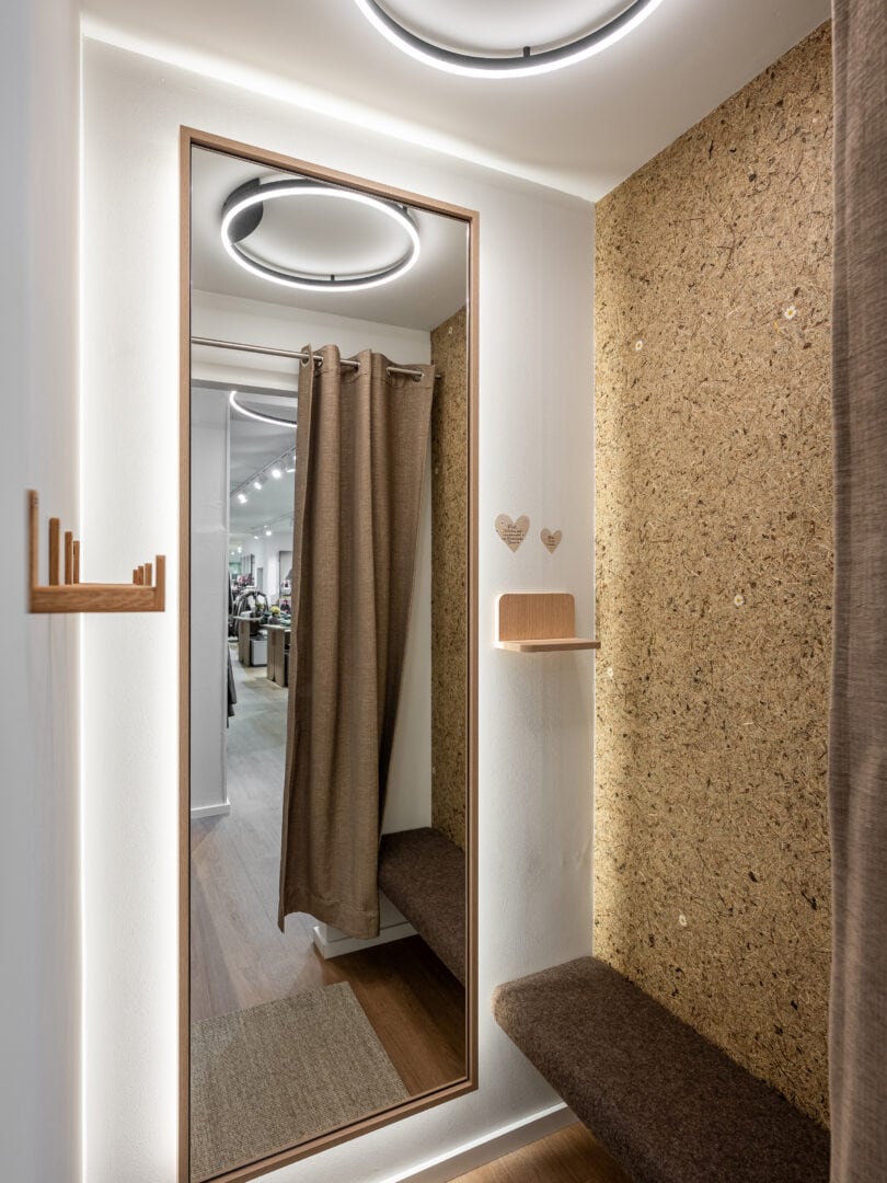 Kleines Ankleidezimmer mit großem Wandspiegel, Sitzbank und dekorativen Herzen an der Wand, moderne Beleuchtung an der Decke.