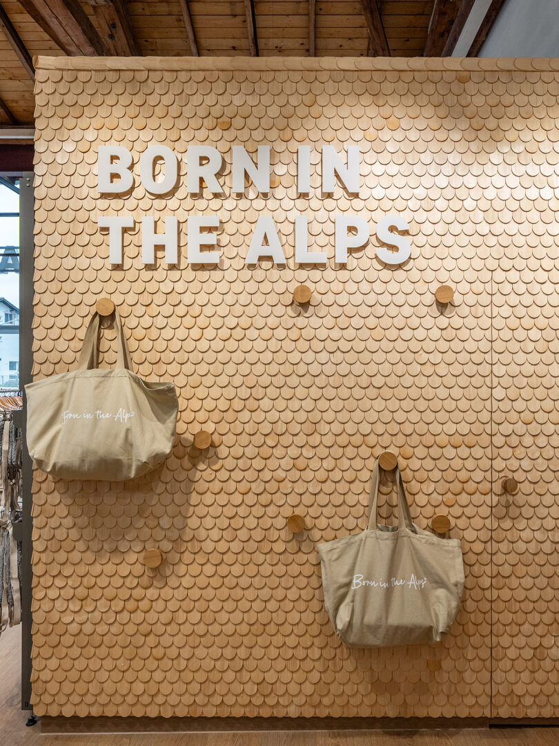 Wanddekoration mit Text 'BORN IN THE ALPS' und zwei Taschen in einem Geschäft.